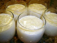 four glasses filled with liquid sitting on top of a counter