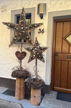 two wooden star decorations on top of stumps in front of a building with a door