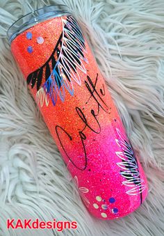 this is an image of a pink and blue glitter tumbler with feathers on it