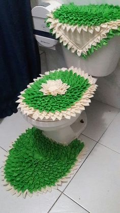 two toilet covers made out of green and white paper on the floor in a bathroom