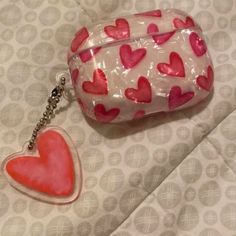 a pink and red heart shaped keychain sitting on top of a bed