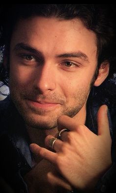 a close up of a person with a ring on his finger and wearing a jacket