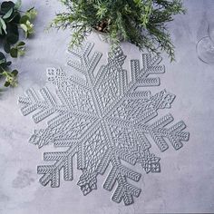 a snowflake is sitting on the ground next to some plants and wine glasses