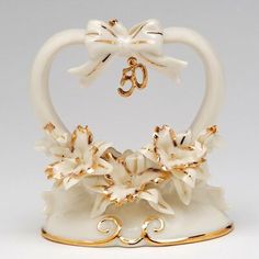 a white and gold figurine shaped like a heart with flowers on the bottom