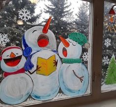 two snowmen are standing next to each other in front of a window