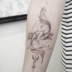 a woman's arm with a tattoo on it that has an image of a fish and stars