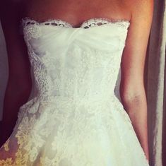 a woman in a wedding dress is holding her hand on the back of her dress