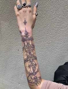 a woman's arm with tattoos on it and two rings around her wrist,