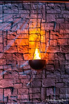 a brick wall with a lit candle hanging from it