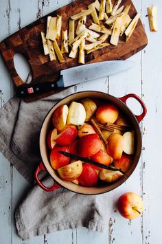 apples and cheese are in a pan on a table next to a cutting board with a knife