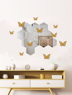 a white dresser sitting next to a mirror with gold butterflies on the wall above it