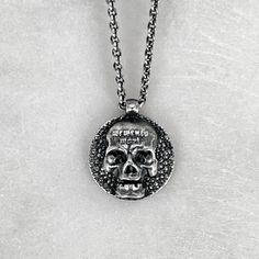 "The Memento Mori Pendant is not just a piece of jewellery; it is a talisman of empowerment and introspection. By wearing this pendant, you carry a symbol of your own mortality, inviting reflection and inspiring a deeper appreciation for the fleeting beauty of life. It serves as a reminder to live fully, embracing the joys and challenges that come your way. Disc measures 1.3cm in diameter. Available on a selection of chain lengths. Picture shows 16\" / 18\" chain. Material : 925 Sterling Silver. Gothic Jewelry With Skull Print For Gift, Gothic Sterling Silver Jewelry With Skull Print, Halloween Engraved Skull Ring Gift, Gothic Hand-cast Skull Jewelry, Vintage Skull Print Jewelry Gift, Vintage Skull Print Jewelry As Gift, Vintage Skull Print Jewelry For Gift, Symbolic Skull Jewelry With Oxidized Finish, Halloween Skull Jewelry With Engraving