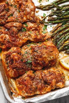 grilled chicken and asparagus in a pan with lemon wedges on the side