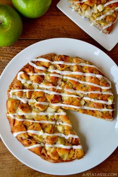 two slices of apple pie with white icing on a plate next to green apples