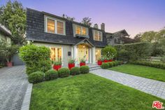 a house that is in the middle of a yard with hedges and bushes around it