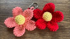 two crocheted flower keychains sitting on top of a wooden table