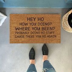 a person standing in front of a door mat that says hey ho, how you doing? where you been? probably doing no stuff cause there you ho