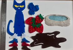 felt cut outs are arranged in the shape of cats and strawberries on a white surface