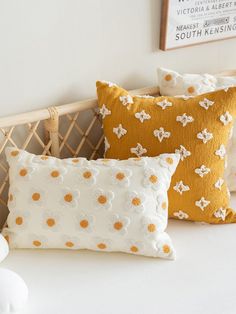 three decorative pillows on a bed in a room with white walls and wood headboard