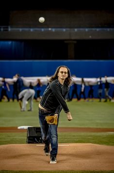 a man throwing a baseball on top of a baseball field with people in the background