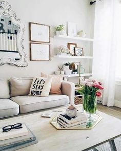 a living room filled with furniture and flowers on top of a coffee table in front of a window