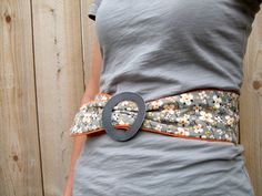 the woman is wearing a gray shirt and has a flowered belt on her waist