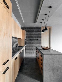 an industrial kitchen with wooden cabinets and black counter tops, along with brick wall in the background