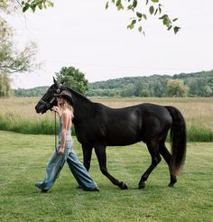 a woman walking her horse through the grass