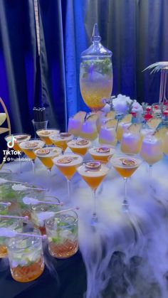 a table topped with lots of glasses filled with different types of drinks and desserts