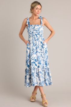 Unleash your inner flower child with our Meadow Muse White & Blue Floral Midi Dress. Perfect for picnics, festivals, and everyday wear, this dress features a stunning floral design in white and blue. With a comfortable fit and lightweight fabric, you'll feel like you're dancing through a meadow all day long. This dress features a square neckline, self-tie shoulder straps, ruching in the bust and waist, a thick elastic waistband, functional hip pockets, and a single tier. 95% Rayon, 5% Linen Hand Wash Cold Lined 95% Rayon, 5% Linen Manufactured in China Designed in the USA Model is wearing a size small Tropical Print Maxi Dress, Blue Floral Midi Dress, Sorority Rush Dresses, Rush Dresses, Cardigan Crop Top, Dress Bra, Little White Dresses, Flower Child, Floral Midi Dress