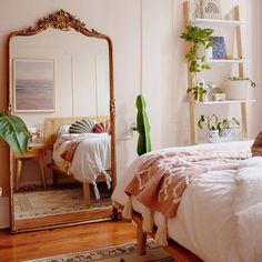 a bedroom with a bed, mirror and plants