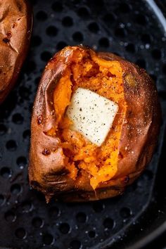 two baked sweet potatoes sitting on top of a black grilling pan with cheese in the middle