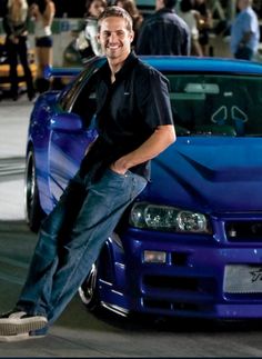 a man leaning on the hood of a blue car