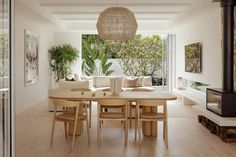 a dining room table and chairs in front of a large window with plants on it