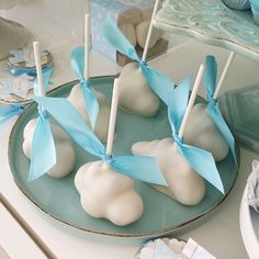 white cake pops with blue bows on a plate