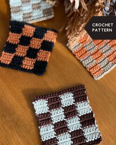 three crocheted squares sitting on top of a wooden table next to a vase with flowers