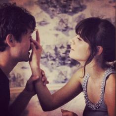 a young man and woman are touching each other's foreheads in front of a floral wallpaper