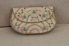 a white purse with flowers on it sitting on top of a table next to a wall