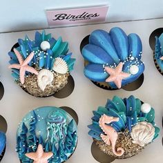 cupcakes decorated with blue frosting and seashells