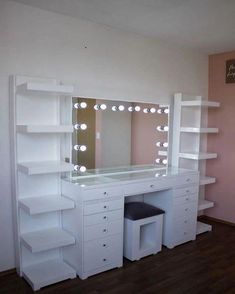 a white vanity with lights on it in a room next to a mirror and shelves