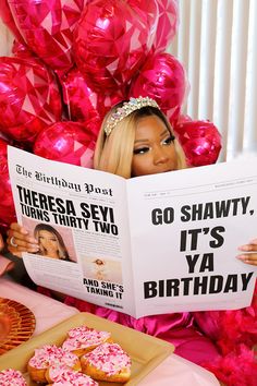 a woman reading a magazine about her birthday with donuts and balloons in the background