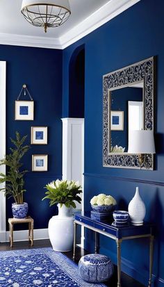 a blue and white living room with flowers in vases on the side table, mirror above