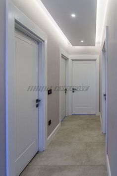 an empty hallway with two white doors leading to another room