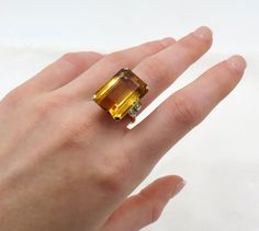 Circa 1940.  Striking emerald cut natural citrine quartz. Beautiful, warm, radiant golden/orange color!  The shoulders of the ring are each accented with  two (2) bead set, round single cut diamonds. The gallery and the shank are done in a quintessential retro design. Size 8.25  and can be sized. This original 1940's/Retro era ring is accompanied by and independent written appraisal/GIA/GG cert. Appraisal Value: $3,500.00 Thank you for visiting.  Any questions, feel free to contact me.  I'm happy to help. Luxury Citrine Topaz Ring With Emerald Cut, Luxury Rectangular Topaz Ring For Formal Occasions, Luxury Formal Rectangular Topaz Ring, Luxury Gold Rectangular Topaz Ring, Retro Era, Bead Set, Natural Citrine, I'm Happy, 14kt Gold