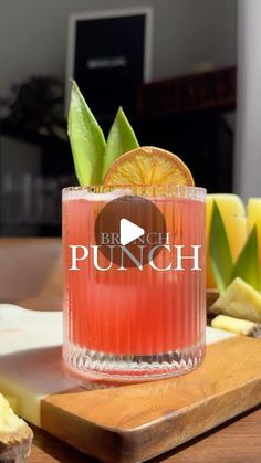 a glass filled with orange juice sitting on top of a wooden cutting board