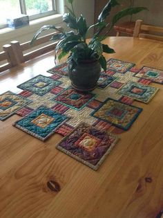 a potted plant sitting on top of a wooden table next to two place mats