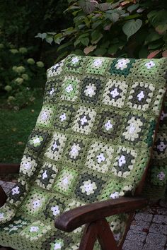 a green and white crocheted blanket sitting on top of a wooden chair