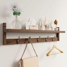 a wooden shelf with two hooks and a purse hanging on the wall next to it