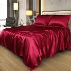 a bed with red sheets and pillows in a room