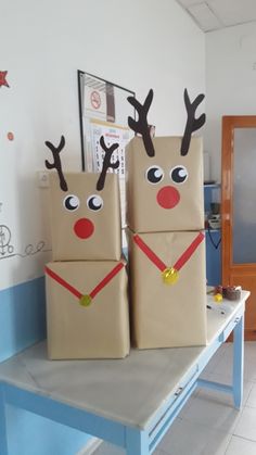 three brown bags with reindeer faces on them are sitting on a table in front of a wall